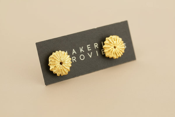 Gold floral earrings on a black card with 'MAKER ROVINS' branding on a light gray background