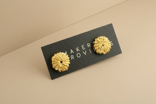 Gold floral earrings on a black card with 'Akerov' branding against a gray background
