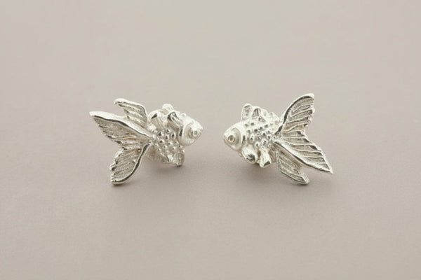 Silver fish-shaped earrings on a gray background