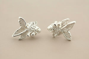 Silver fish-shaped earrings on a dark gray background
