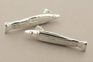 Silver fish-shaped earrings on a gray background