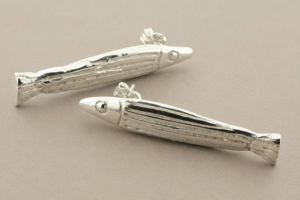 Silver fish-shaped earrings on a gray background