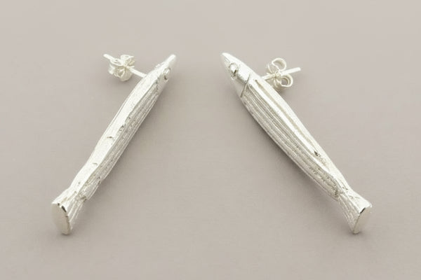 Silver fish-shaped earrings on a gray background