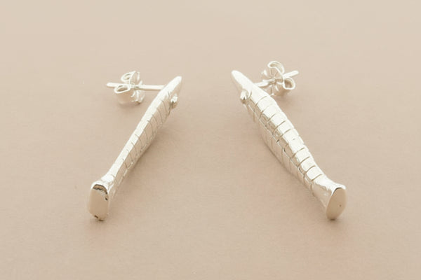 Silver fish earrings on a gray background