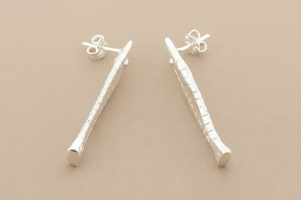 Silver fish earrings on a gray background