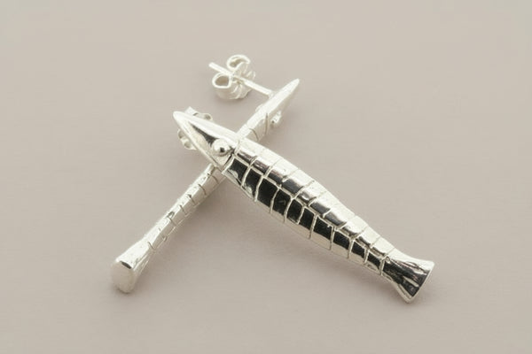 Silver fish-shaped earrings on a gray background