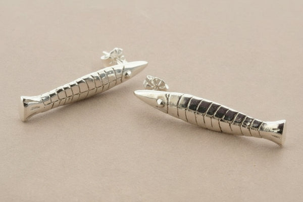 Pair of silver fish-shaped earrings on a gray background