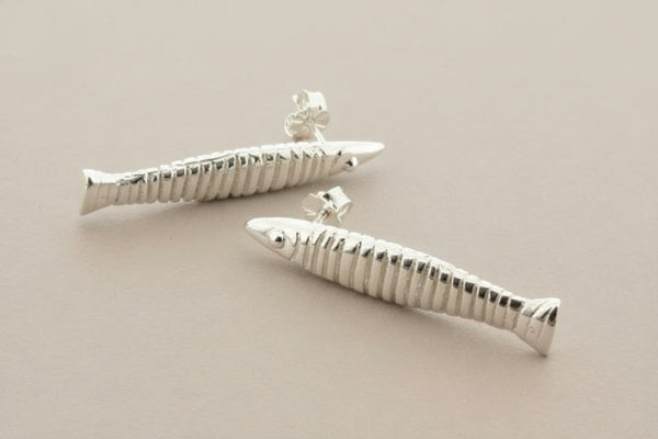 Silver fish-shaped earrings on a gray background