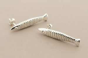 Silver fish-shaped earrings on a gray background