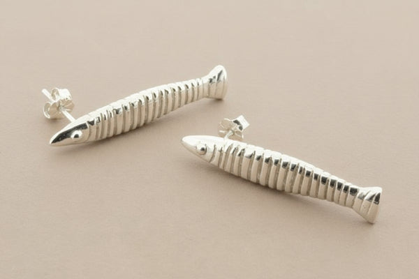 Silver fish-shaped earrings on a gray background