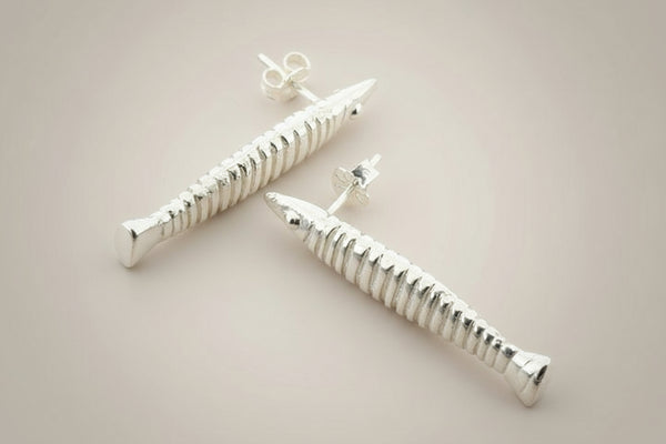 Silver screw-shaped earrings on a gray background