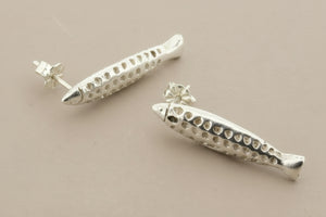 Silver fish-shaped earrings on a gray background