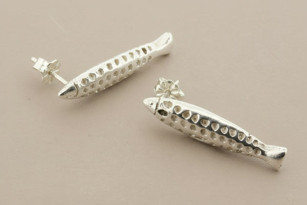Silver fish-shaped earrings on a gray background