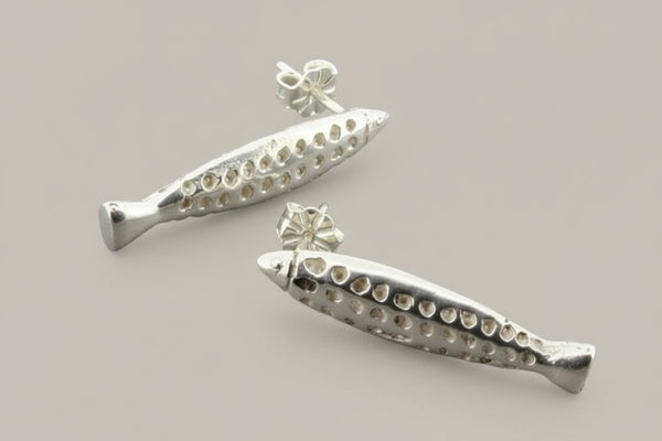Silver fish-shaped earrings on a gray background