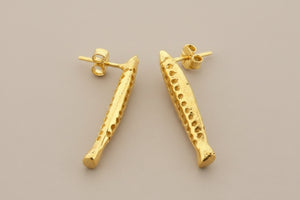 Gold earrings on a gray background