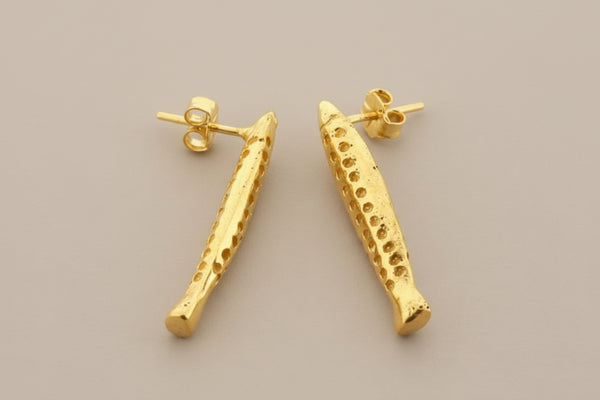 Gold earrings on a gray background