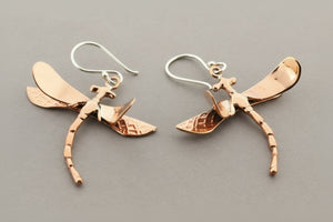 Dragonfly-shaped earrings on a gray background