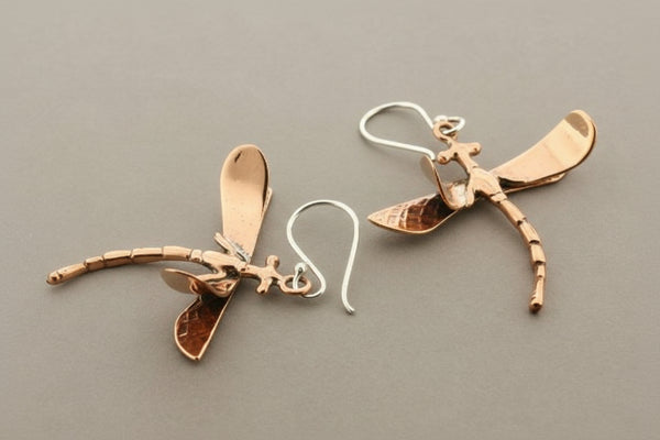 Dragonfly-shaped earrings on a gray background