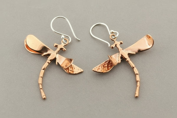 Pair of copper dragonfly earrings on a gray background