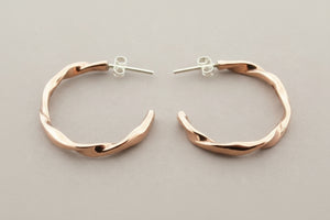 Copper hoop earrings on a gray background