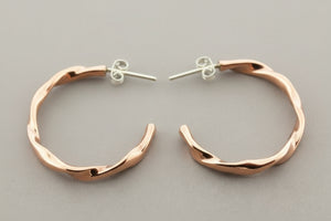 Rose gold hoop earrings on a gray background