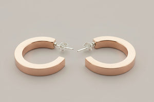 Pair of copper hoop earrings on a gray background