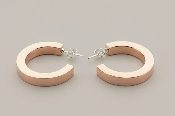 Pair of copper hoop earrings on a gray background