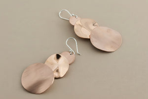 Copper earrings with circular pendants on a dark background