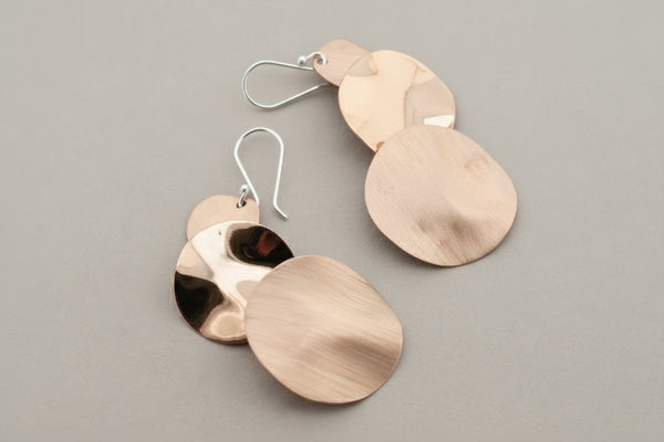 Pair of copper disc earrings on a dark gray background