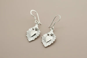 Silver heart-shaped earrings on a dark gray background