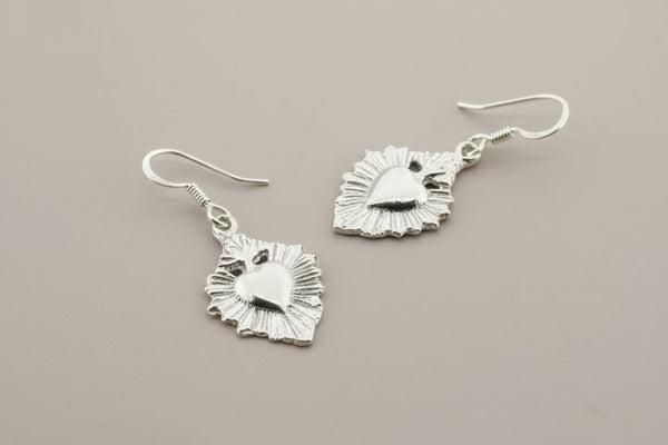 Silver earrings with intricate designs on a gray background