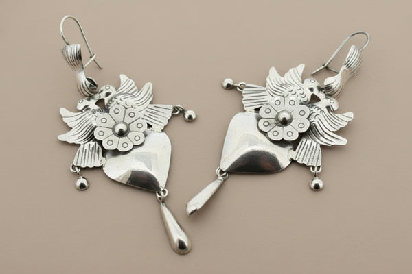 Pair of silver earrings with floral designs on a gray background