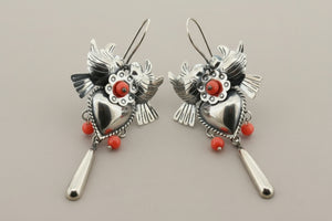 Pair of silver heart-shaped earrings with red accents on a gray background