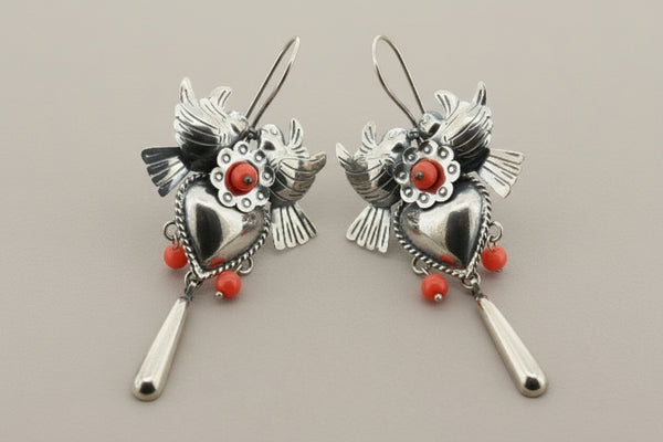 Pair of silver heart-shaped earrings with red accents on a gray background