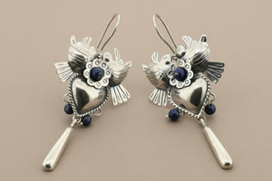 Pair of silver heart-shaped earrings with blue stones on a gray background
