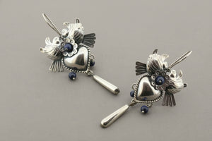Pair of silver heart-shaped earrings with blue gemstones on a gray background