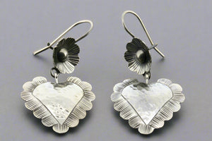 Silver heart-shaped earrings on a gray background