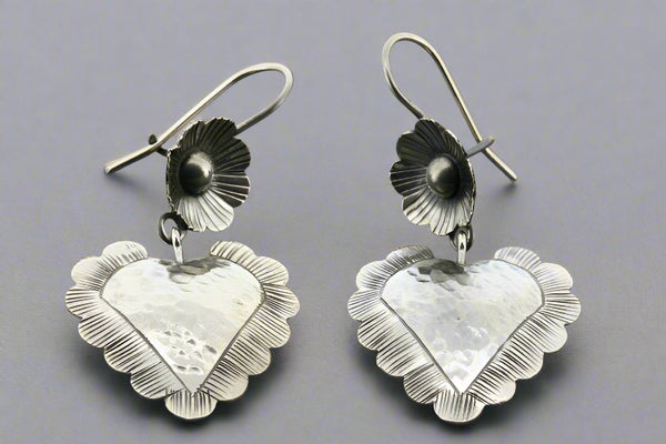 Silver heart-shaped earrings on a gray background