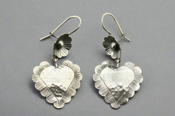 Pair of silver heart-shaped earrings on a gray background