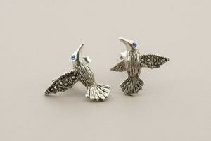 Pair of silver bird-shaped earrings on a gray background