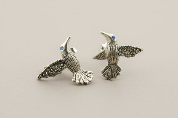 Pair of silver bird-shaped earrings on a gray background