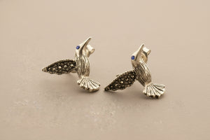 Silver hummingbird earrings on a gray background