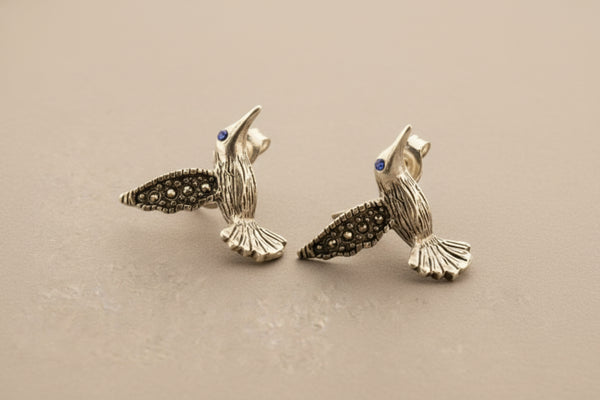 Silver hummingbird earrings on a gray background