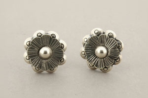 Pair of silver floral earrings on a gray background