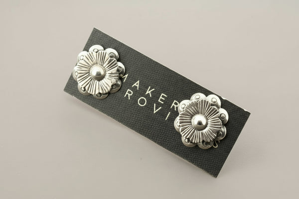Pair of silver floral earrings against a gray background