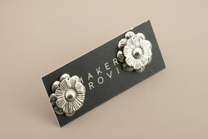 Pair of silver floral earrings against a gray background