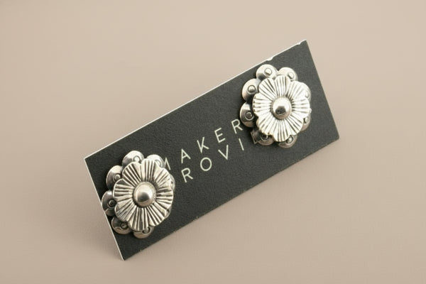 Pair of silver floral earrings against a gray background