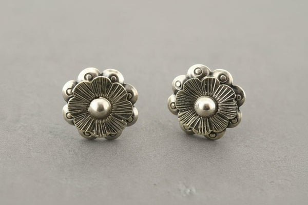 Pair of silver floral stud earrings on a gray background