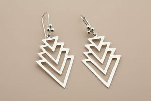 Pair of silver geometric earrings on a dark gray background