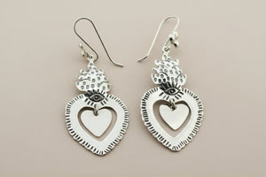 Silver heart-shaped earrings on a dark gray background